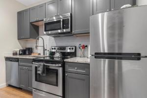 a kitchen with stainless steel appliances and gray cabinets at Lovely 1-BR Suite in the Heart of Adams Morgan in Washington, D.C.