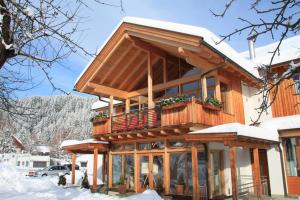 uma casa de madeira com uma varanda na neve em Alpencamp Kärnten em Kötschach-Mauthen