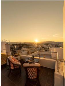 einen Balkon mit einem Tisch und Stühlen sowie Blick auf den Sonnenuntergang in der Unterkunft Luxury Town Center Suite, Β1 in Iraklio