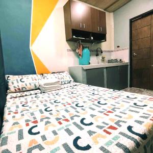 Un dormitorio con una cama con un edredón colorido. en Transient Siete Barcelone B&B -Studio Type Valleyhomes Patul, en Plaridel