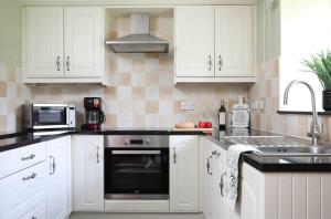 a kitchen with white cabinets and a black oven at Greenfinch in Lucker