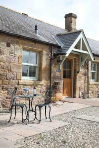 two benches sitting in front of a stone house at Greenfinch in Lucker