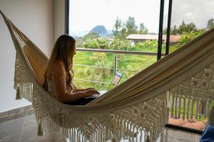 a woman sitting in a hammock with a laptop at Roble Colonial - Apartamentos Deluxe en Guatapé in Guatapé