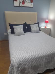 ein großes Bett mit blauer und weißer Bettwäsche und einer roten Lampe in der Unterkunft Bungalow los angeles in Villa Elisa