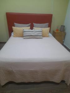 ein großes weißes Bett mit einem roten Kopfteil und Kissen in der Unterkunft Bungalow los angeles in Villa Elisa