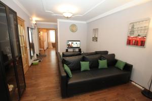 a living room with a black couch with green pillows at TVST Apartments Belorusskaya in Moscow