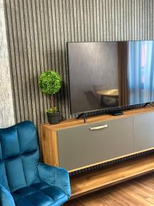 a living room with a tv and a blue chair at West Point Luxury studio in Plovdiv