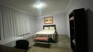 a bedroom with a bed and a chair in it at Triboulet hospedaria in Campinas
