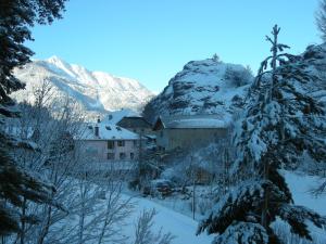 a village covered in snow with mountains in the background at Gîte Auberge Les Terres Blanches de Méolans in Méolans