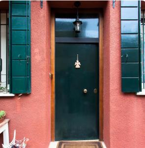 a green door on a red building with green shutters at Dorsoduro House in Venice