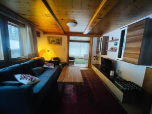 圣尼克劳斯5 Zimmer-Wohnung mit Garage und Sauna的客厅设有蓝色的沙发和木制天花板。