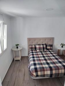 een slaapkamer met een bed met een geruite deken bij Casa del Tío Paco in Montecorto