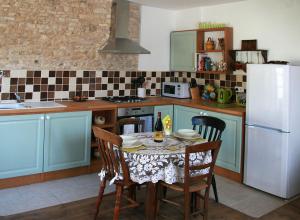 a kitchen with a table with chairs and a white refrigerator at La Greletterie in Champagné-le-Sec