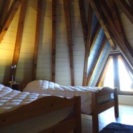 a attic room with a bed and two windows at Moulin De Rouzé in Castelnaud-de-Gratecambe