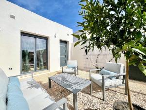 a patio with a couch and chairs and a tree at Le Jasmin 1 - Chic, Clim, Terrasse, Neuf, 4 personnes in Fos-sur-Mer