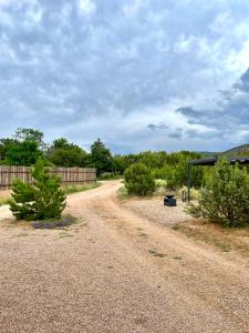a dirt road next to a fence and trees at CASA TUA SANTA FE - NM Farmhouse Sanctuary Soaking Room 1 acre private in Santa Fe