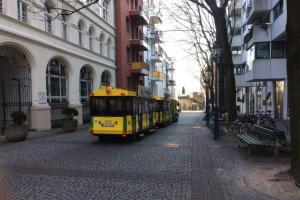 a yellow bus driving down a street next to buildings at Köln Altstadt Charmantes Studio in Cologne +1 photo