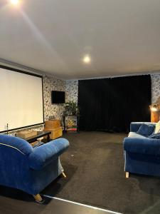 a living room with two blue couches and a screen at Paton Place Harbour Hillviews in  Lyttelton