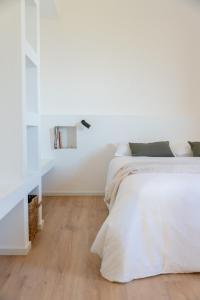 a white bedroom with two beds and a wooden floor at La casa di Ernino in Tortoreto Lido