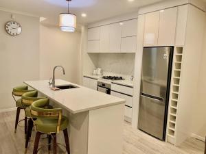 a kitchen with white cabinets and a counter with bar stools at Lifestyle with Tennis Court in Tamahere +18 photos