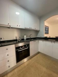 eine Küche mit weißen Schränken und einem schwarzen Backofen in der Unterkunft EL ESCONDITE Bahía de Vera Naturista in Playas de Vera