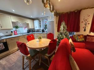a kitchen with a table and a christmas tree at London 2 double bedrooms 2 Bathrooms Holiday Home - Parking SKYSPORTS, NETFLIX - 2 - 3 minutes walk to the Train station - 19min to London Liverpool Street fast Internet GROUND FLOOR 100s of shops restaurants bakeries 24-hour ASDA superstore, Major hospi in London