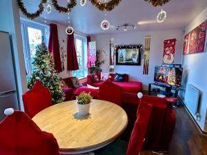 Sala de estar con mesa y árbol de Navidad en London 2 Bed 2 Bath Apartment Holiday Home - Free Parking - 3min walk to the Train station - 19min to London Liverpool Street 5min to Victoria Line 1GB Broadband super fast Internet GROUND FLOOR 100s of shops restaurants bakeries 24-hour ASDA superstore, en Londres