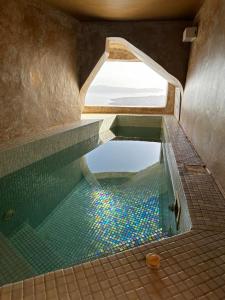 una piscina d'acqua in bagno con finestra di Maria Paradeiso Resorts a Imerovigli