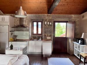 a kitchen with white cabinets and a wooden ceiling at Casa María da Reza in Ribadavia