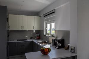 a kitchen with white cabinets and a bowl of fruit on a counter at Anna Maria's Maisonette I in Kardamaina