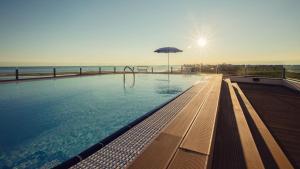 a swimming pool with an umbrella and the ocean at Residence al Bosco in Grado