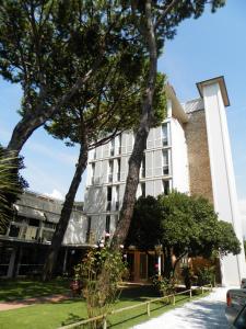 a white building with trees in front of it at Hotel Il Caravaggio in Marina di Pietrasanta