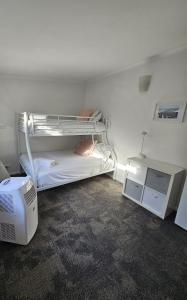a room with two bunk beds and a desk at Cygnets in Lake Munmorah