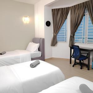 ein Hotelzimmer mit zwei Betten und einem Schreibtisch in der Unterkunft Tebrau City Residence by Natol in Johor Bahru