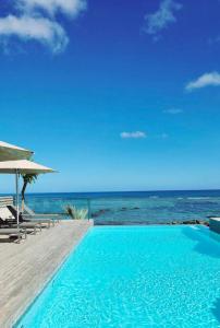 a blue swimming pool next to the ocean at Beachfront Chic Penthouse in Rivière Noire