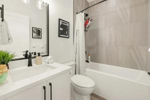 a white bathroom with a toilet and a tub and a sink at Cozy Saanich Cottage ideal location to UVIC and Downtown in Victoria