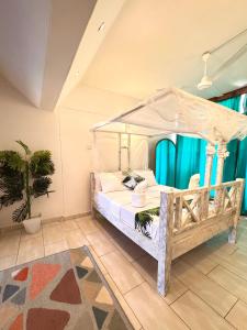 a bedroom with a canopy bed and a potted plant at Bahari Studio Beach Front Apartment. in Diani Beach