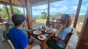 a man and woman sitting at a table eating food at Frangipani Inn & Restaurant in Seraya