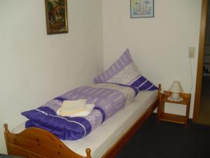 ein kleines Bett in einem Zimmer mit violetter Bettwäsche in der Unterkunft Ferienhaus Tobie in Ahlefeld