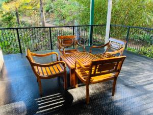 three chairs and a wooden table and bench on a porch at Agarapathana Estate Holiday Bungalow in Hatton