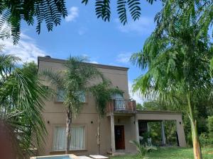 a house with a balcony and palm trees at Alojamiento la irene in Paso de la Patria