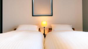 two white beds in a room with a lamp at Homey Inn in Kyoto