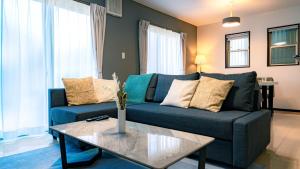 a living room with a blue couch and a table at Homey Inn Kujo Kawaramachi in Kyoto