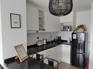 a kitchen with white cabinets and a black refrigerator at Departamento encanto del sur isla teja in Valdivia