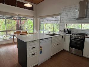 a kitchen with a sink and a stove top oven at Kookaburra Villa 629 at Kingfisher Bay Resort K'Gari Fraser Island in Kingfisher Bay