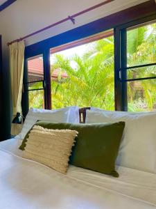 ein Bett mit einem Kissen und einem Fenster in der Unterkunft Villa Dua - Beachfront Sunset Garden Villa in Nathon Bay