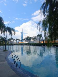 a swimming pool with palm trees and a building in the background at Trion Residence Kuala Lumpur by Infinity in Kuala Lumpur