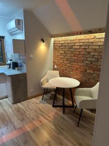 a room with a table and chairs and a brick wall at Pokoje przy Kawiarence 2 in Rewa