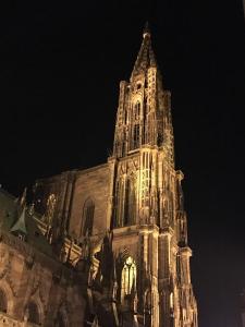 un gran edificio con una torre de reloj por la noche en Adonis Hotel Strasbourg en Estrasburgo