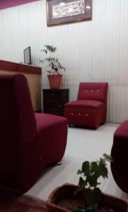 a living room with two red chairs and a plant at Sweet home in Karawang